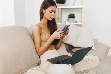 Smiling woman working on laptop in cozy living room, enjoying online freelance job and connecting with technology.
