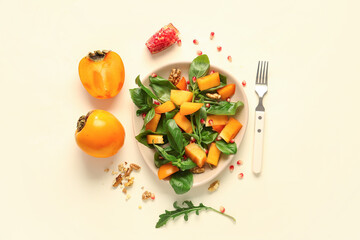 Plate of delicious salad with persimmon, walnut and pomegranate seeds on yellow background