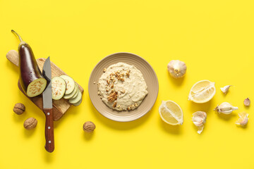Plate of tasty baba ghanoush with ingredients on yellow background