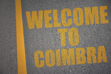 asphalt road with text welcome to Coimbra near yellow line.