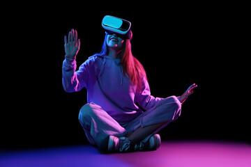 Young woman using VR glasses on dark background