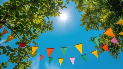 colorful pennant string decoration in green tree foliage on blue sky, summer party background template banner with copy space