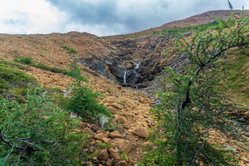 Fototapeta premium Tablelands in Gros Morne National Park, a Canadian national park and World Heritage Site in Newfoundland. An area where earth's mantle is exposed, peridotite rocks rich with iron rust, waterfall.