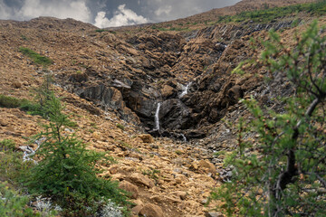 Tablelands in Gros Morne National Park, a Canadian national park and World Heritage Site in Newfoundland. An area where earth's mantle is exposed, peridotite rocks rich with iron rust, waterfall.