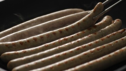 Turning Weisswurst Sausages on a Searing Grill Pan. Selective focus, close-up.