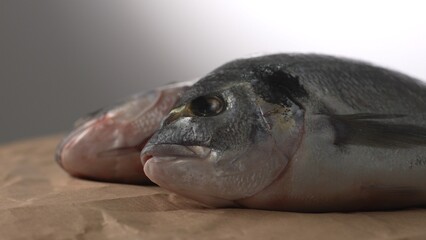 Raw fish Dorado on a paper-covered surface. Selective focus, close-up.