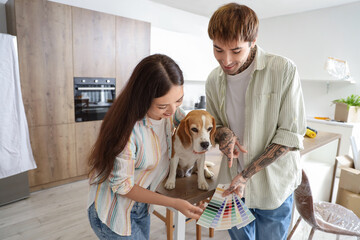 Young couple with paint color palettes and Beagle dog during repair in their new house