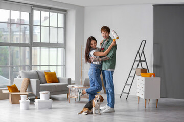 Fototapeta na wymiar Young couple with Beagle dog hugging during repair in their new house