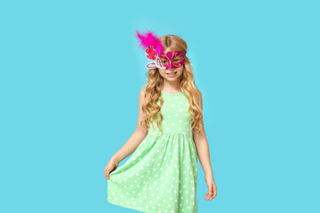Funny little girl wearing carnival mask on blue background