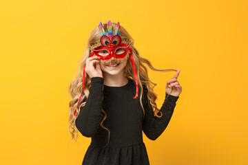 Pretty little girl wearing carnival mask on yellow background