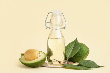 Fresh ripe avocado and glass bottle with essential oil on beige background
