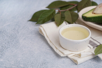 Bowl of essential oil with napkin and leaves on grunge grey background