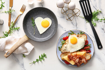 Composition with tasty fried eggs, cut croissant, tomatoes and arugula on light background