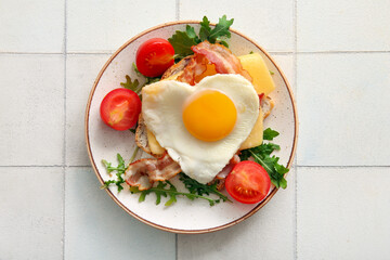Plate with tasty fried egg, toast, bacon, tomatoes and arugula on light tile background