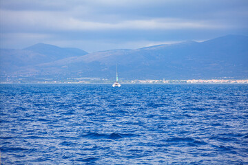 Boat at blue sea with blue mountains at background