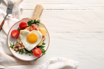 Plate with tasty fried egg, toast, tomatoes and arugula on light wooden background