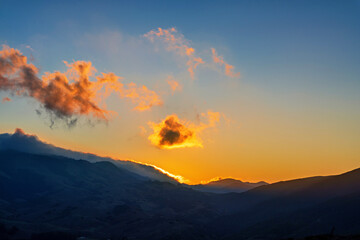Sunrise in the mountains with glowing clouds