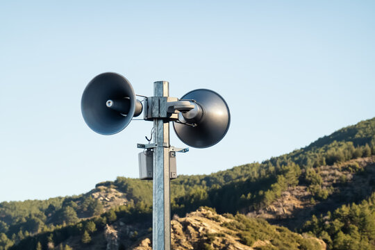 Loudspeakers on pole. Two public address system speakers on blue sky and mountains background