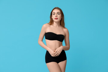 Obraz premium Beautiful young woman in black underwear on blue background
