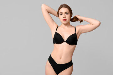Fototapeta premium Attractive young woman in black underwear on light background