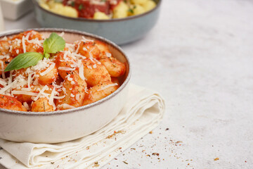 Bowl of tasty gnocchi with cheese on white background