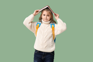 Little schoolgirl with book  on green background