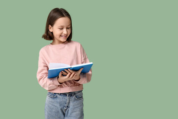 Little girl reading book on green background