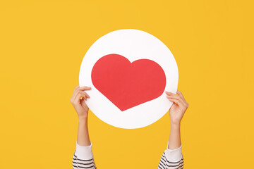 Female hands with heart like icon on yellow background