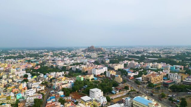 Densely populated Indian cityscape of Tiruchirappalli with diverse architecture at dusk and the Malaikottai Rock Fort in the background. Aerial view, Tamil Nadu, China