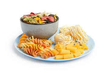 Plate and bowl with different uncooked pasta on white background