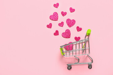 Small shopping cart with paper hearts on pink background. Valentine's Day celebration © Pixel-Shot