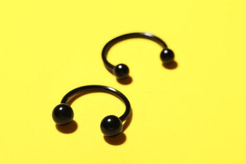 Circular barbells for piercing on yellow background