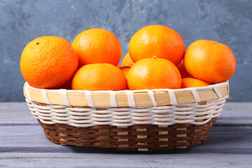 Basket with tasty tangerines on grey wooden table