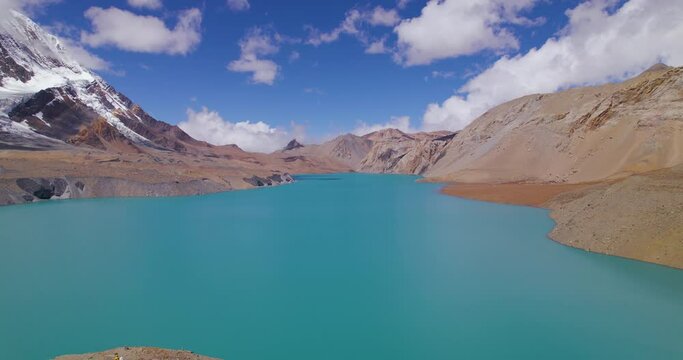 Drone shot of Tilicho Lake at Annapurna mountain circuit, World's highest altitude lake under blue cear sky with clouds, mountains, happy nature, chilly weather Nepal 4K