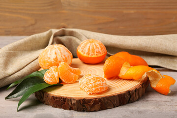 Board with tasty tangerines and leaves on grey wooden table