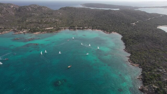 Cinematic aerial view of beautiful sailboats sailing over the sea of ​​the island of Caprera in Sardinia. Cala Conchiglia.