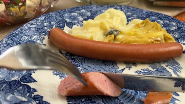 Eating typical German bockwurst sausage and homemade potato salad close up personal perspective