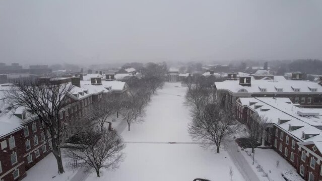 Snow day University of Delaware drone reverse ascending long shot. Heavy snow falling