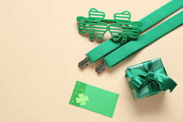 Plastic eyeglasses with gift box and suspenders on beige background. St. Patrick's Day celebration
