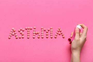 Child's hand with inhaler and word ASTHMA made of pills on pink background - obrazy, fototapety, plakaty