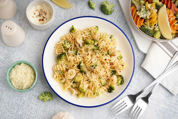 Delicious fusilli pasta with broccoli and cheese in bowl on light background