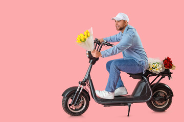 Fototapeta na wymiar Delivery man with flowers driving scooter on pink background