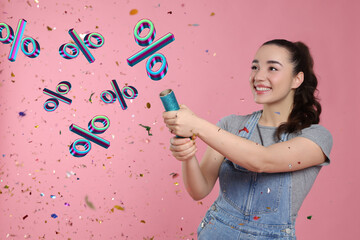 Discount offer. Happy young woman blowing up party popper on pink background. Confetti and percent signs in air