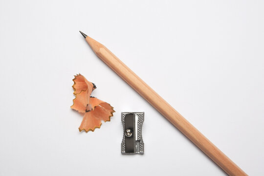 Graphite pencil, sharpener and shavings on white background, flat lay