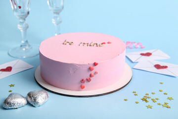 Pink bento cake with envelopes and candies on blue background. Valentine's Day celebration