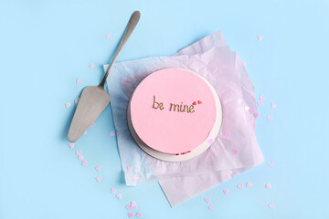 Pink bento cake with spatula and confetti on blue background. Valentine's Day celebration