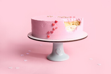 Stand with bitten bento cake on pink background. Valentine's Day celebration