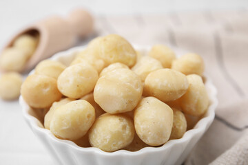 Fototapeta na wymiar Tasty peeled Macadamia nuts in bowl on table, closeup