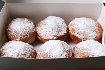 Delicious sweet buns with powdered sugar in box, closeup