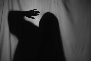Silhouette of creepy ghost behind grey cloth
